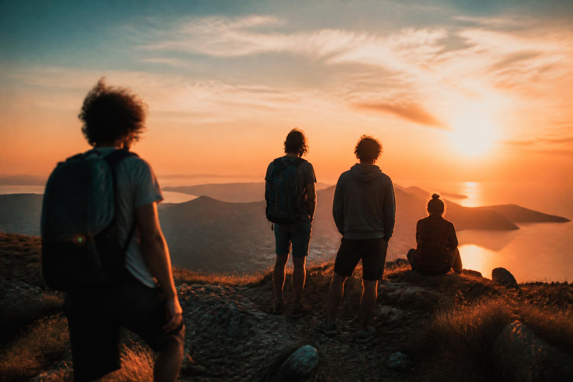 Un piccolo gruppo di amici in vetta al tramonto, con il mare sullo sfondo